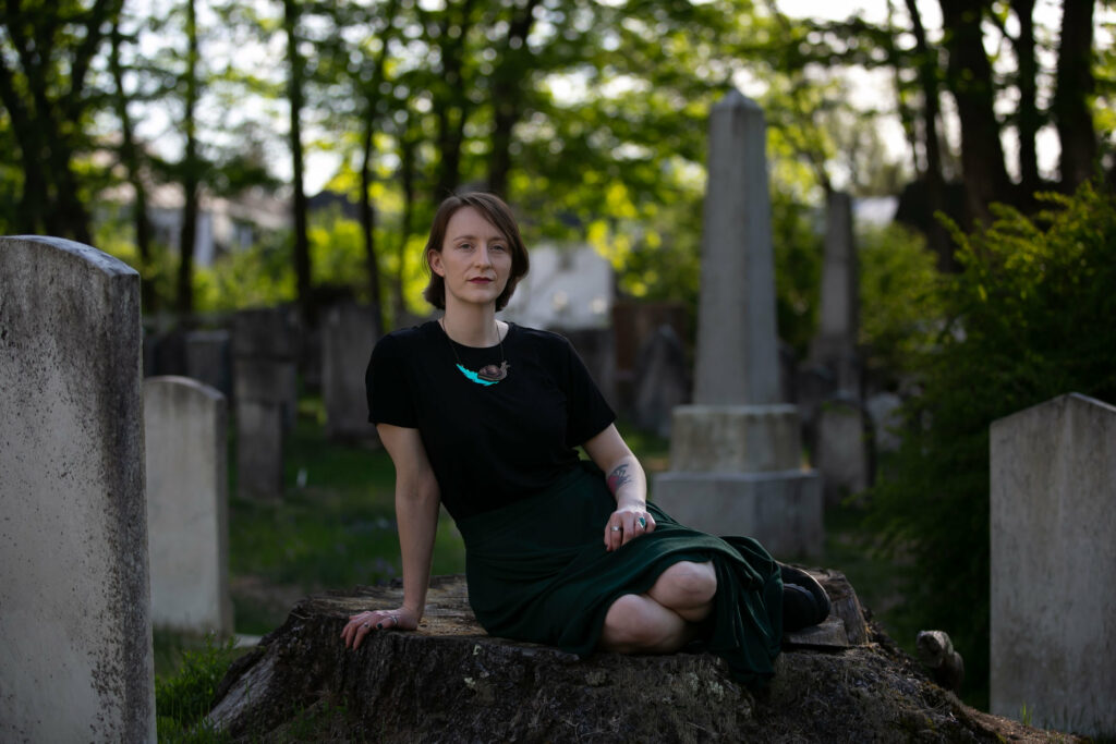 Courtney, sitting on a large stump in a cemetery, surrounded by headstones.